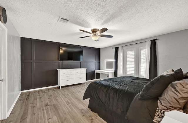 bedroom featuring a textured ceiling, a ceiling fan, wood finished floors, and visible vents