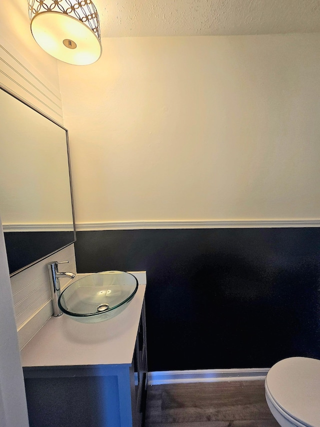 bathroom featuring toilet, a textured ceiling, wood finished floors, and vanity