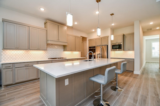 kitchen with visible vents, wood tiled floor, gray cabinets, stainless steel appliances, and a sink