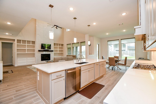 kitchen with a sink, light countertops, appliances with stainless steel finishes, wood tiled floor, and an island with sink