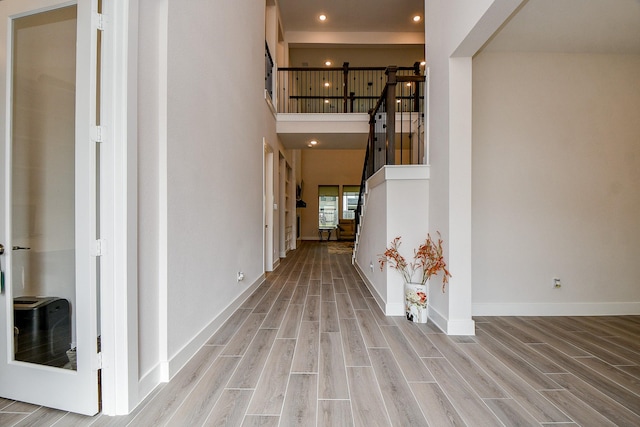 foyer featuring recessed lighting, a towering ceiling, baseboards, stairs, and wood tiled floor