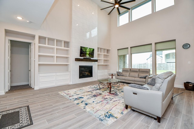 living room featuring recessed lighting, visible vents, wood tiled floor, a tile fireplace, and baseboards