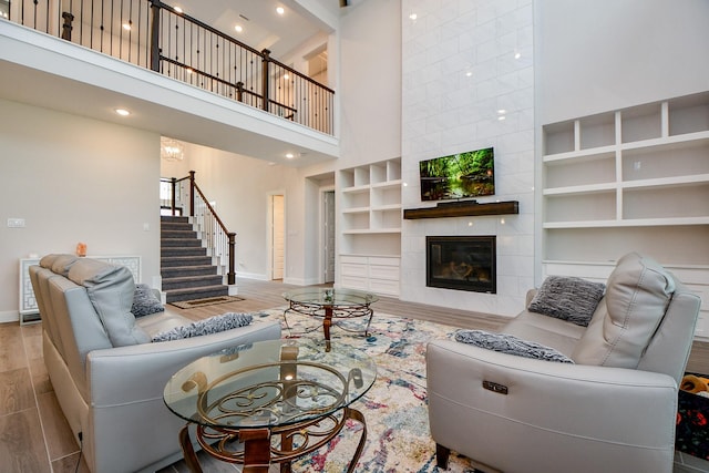 living area featuring baseboards, a fireplace, stairway, and wood finished floors