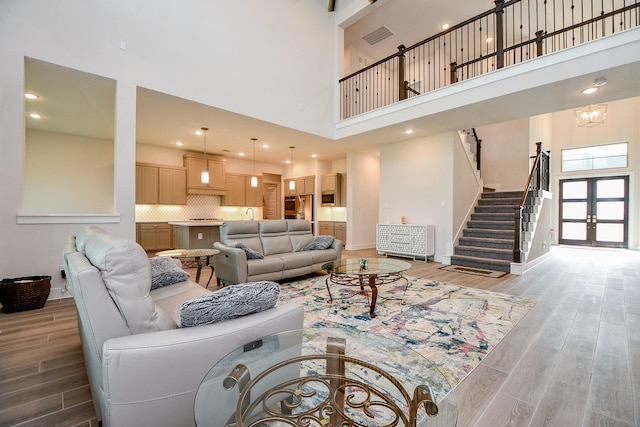 living area with french doors, visible vents, stairway, and light wood finished floors