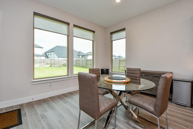 dining space featuring a residential view, baseboards, wood finished floors, and recessed lighting