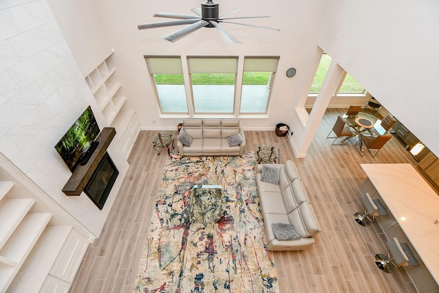 living area with a towering ceiling, baseboards, and wood finish floors