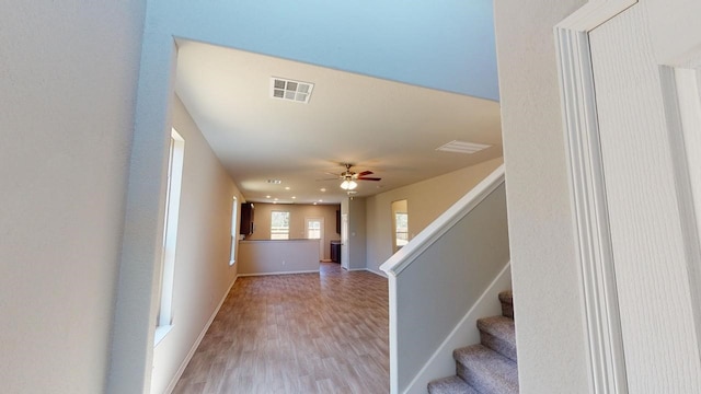 interior space with visible vents, ceiling fan, wood finished floors, baseboards, and stairs