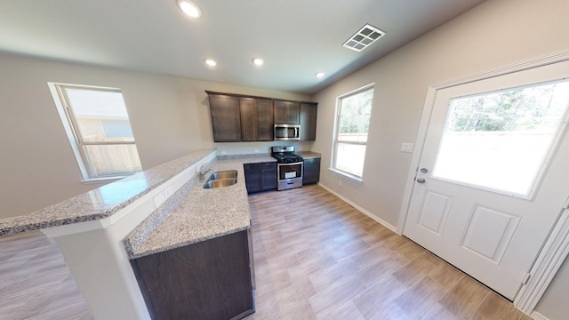 kitchen featuring stainless steel appliances, visible vents, a sink, dark brown cabinetry, and a peninsula