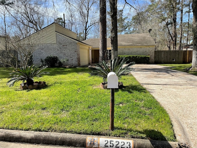 mid-century home featuring a garage, brick siding, fence, driveway, and a front lawn