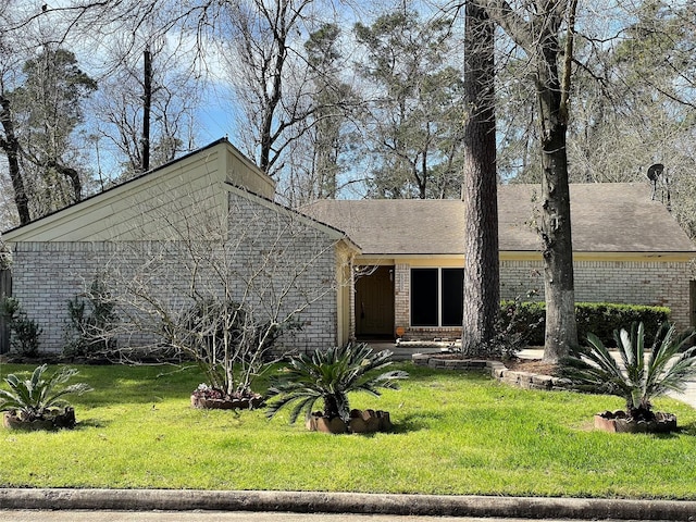 mid-century inspired home featuring a front yard and brick siding