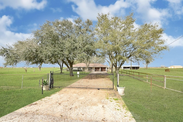 view of front of property with a rural view, a front yard, fence, and a gate