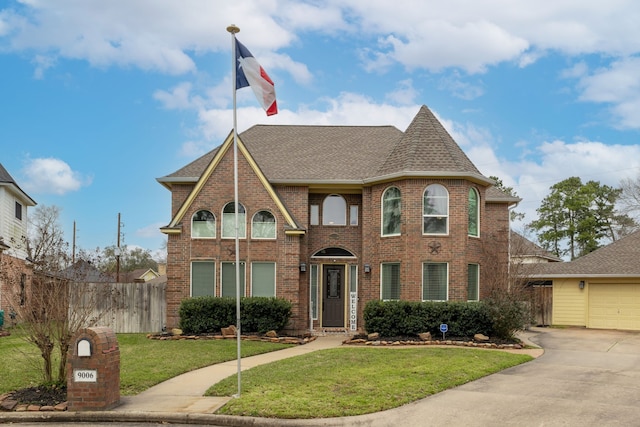 view of front of home with a shingled roof, concrete driveway, fence, a front lawn, and brick siding