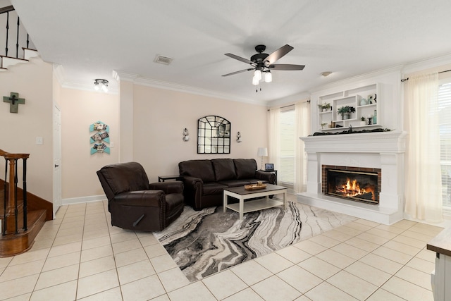 living area with light tile patterned floors, ceiling fan, visible vents, stairway, and crown molding