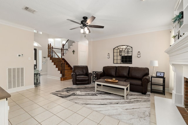 living room featuring a brick fireplace, stairs, visible vents, and ornamental molding