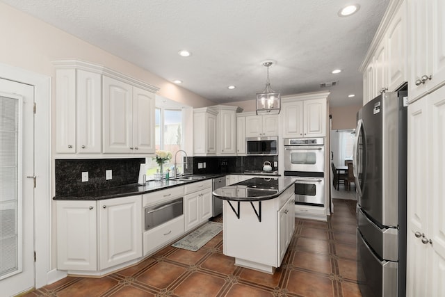 kitchen with appliances with stainless steel finishes, dark countertops, a sink, and a warming drawer