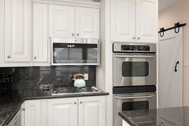 kitchen featuring stainless steel appliances, white cabinets, backsplash, and a barn door