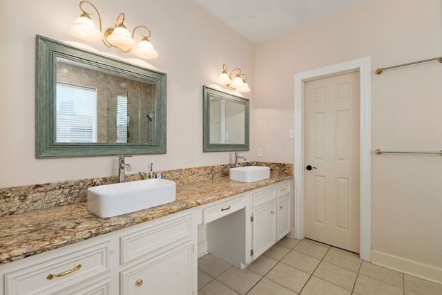 bathroom with double vanity, tile patterned flooring, a tile shower, and a sink