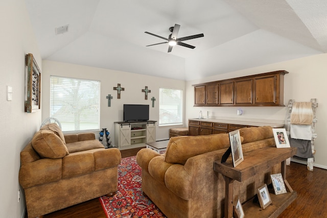 living area featuring a ceiling fan, visible vents, a raised ceiling, and dark wood-type flooring