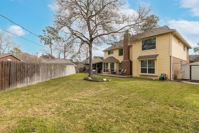 back of house with an outbuilding, a fenced backyard, a lawn, a chimney, and a patio area