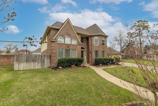 view of front of home featuring brick siding, a front yard, fence, and a shingled roof