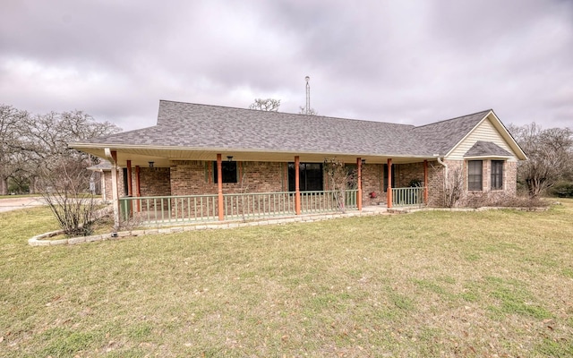 view of front of home with a shingled roof, covered porch, brick siding, and a front lawn