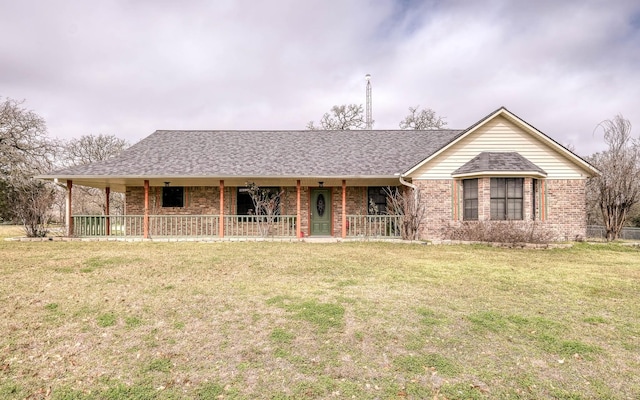 ranch-style home featuring covered porch, brick siding, a front yard, and a shingled roof