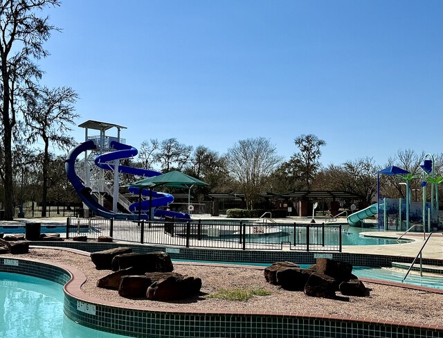 community pool with fence, playground community, and a water slide