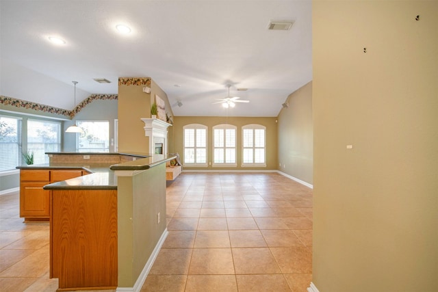 kitchen with visible vents, lofted ceiling, light tile patterned flooring, a fireplace, and plenty of natural light