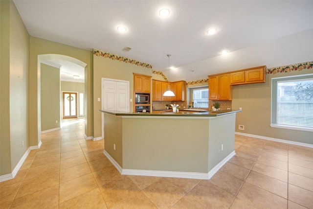 kitchen with dark countertops, stainless steel microwave, arched walkways, and oven