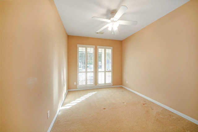 spare room with baseboards, light colored carpet, and a ceiling fan