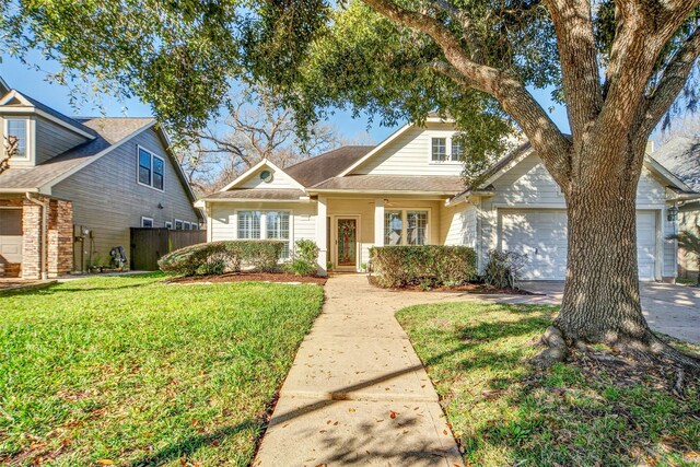 traditional-style home featuring a front lawn, fence, a garage, and driveway