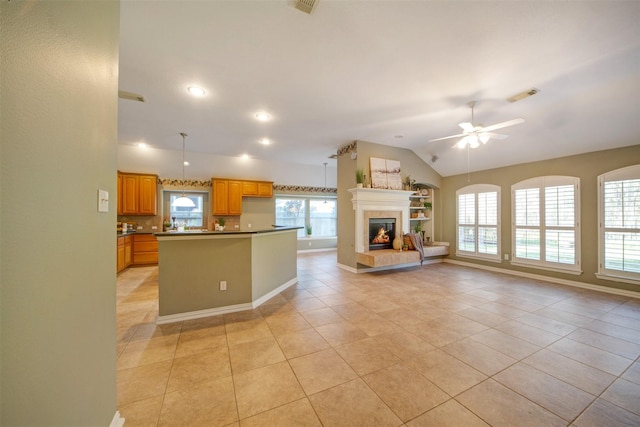 kitchen featuring visible vents, a center island, open floor plan, lofted ceiling, and a fireplace