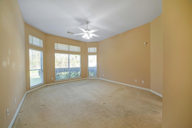 empty room with carpet flooring, visible vents, baseboards, and ceiling fan