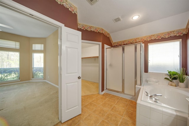 bathroom with visible vents, a walk in closet, baseboards, a garden tub, and a stall shower