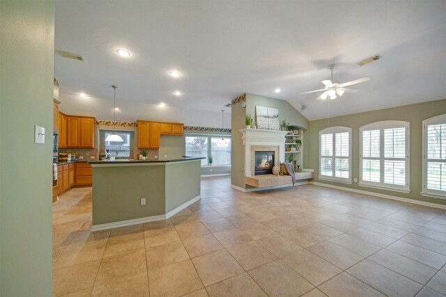 kitchen with dark countertops, visible vents, open floor plan, vaulted ceiling, and a fireplace