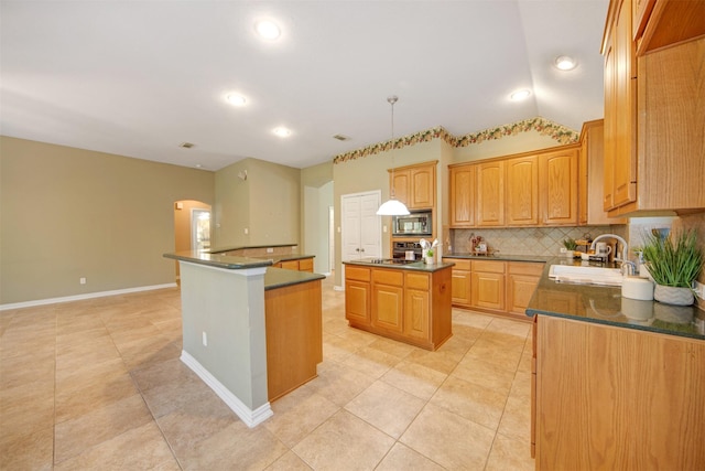 kitchen featuring a sink, stainless steel microwave, dark countertops, and a center island