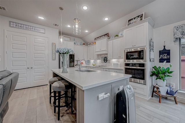 kitchen with stainless steel appliances, a sink, visible vents, white cabinetry, and light countertops