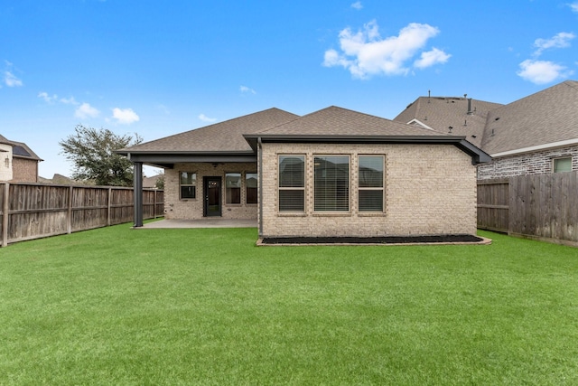 back of house with brick siding, a shingled roof, a lawn, a patio area, and a fenced backyard