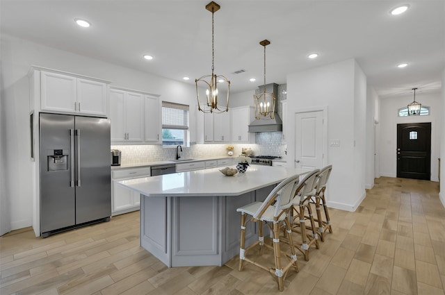 kitchen with custom exhaust hood, decorative backsplash, appliances with stainless steel finishes, white cabinets, and a sink