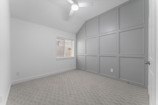 unfurnished bedroom with baseboards, a ceiling fan, vaulted ceiling, carpet floors, and a decorative wall