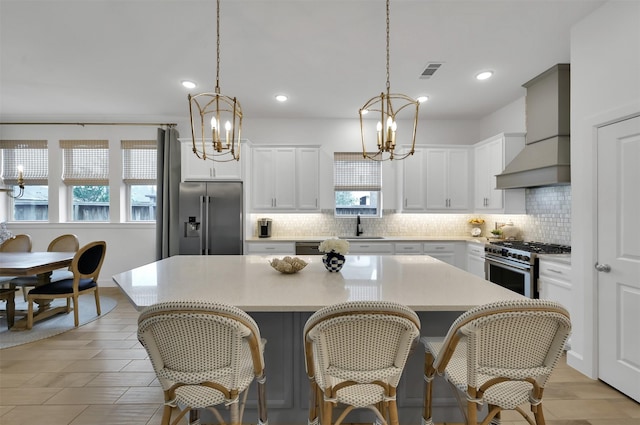 kitchen with a sink, visible vents, high quality appliances, a center island, and custom range hood