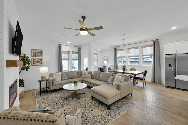 living area featuring a healthy amount of sunlight, light wood-style flooring, a fireplace, and recessed lighting