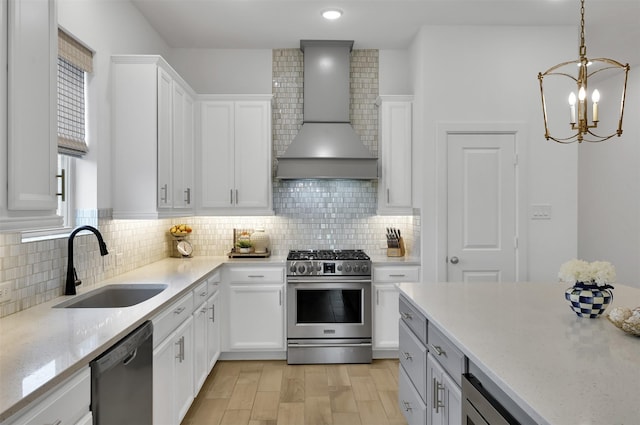 kitchen featuring wall chimney exhaust hood, a sink, gas range, a chandelier, and dishwashing machine