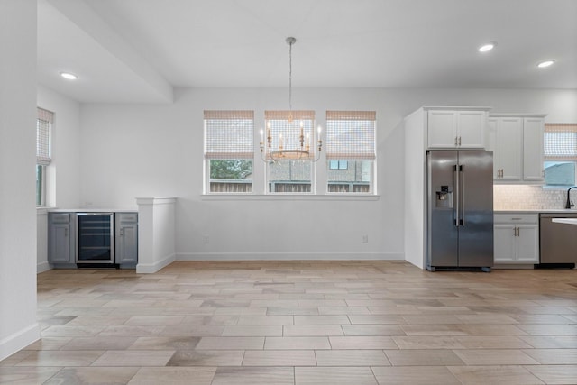 kitchen featuring decorative backsplash, wine cooler, stainless steel appliances, light countertops, and white cabinetry