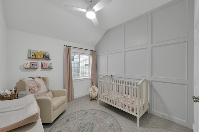 bedroom featuring ceiling fan, a decorative wall, light carpet, vaulted ceiling, and a crib