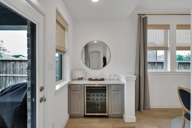 bar featuring wine cooler, baseboards, light wood-style flooring, and a dry bar