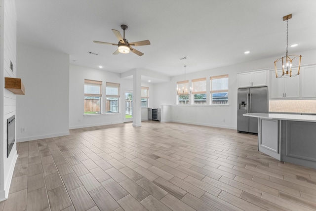 unfurnished living room featuring recessed lighting, a large fireplace, ceiling fan with notable chandelier, visible vents, and light wood-style floors