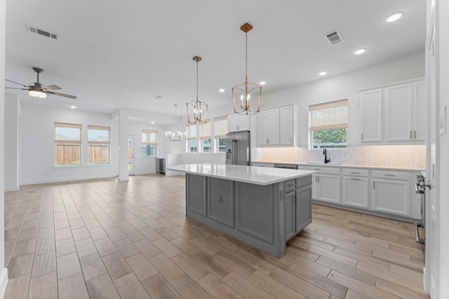 kitchen with gray cabinets, stainless steel fridge, visible vents, and white cabinetry