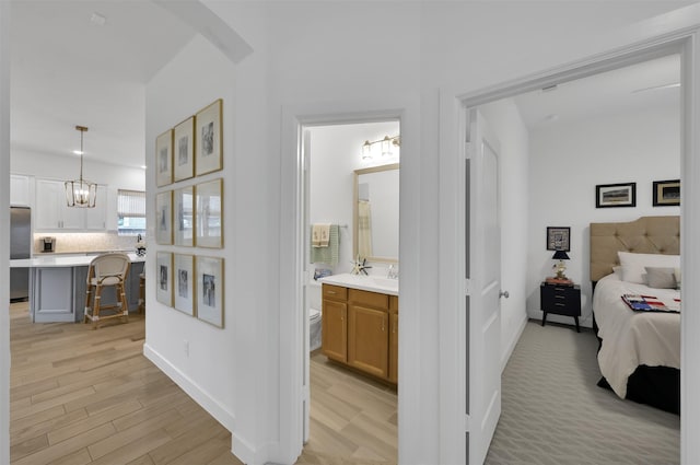 bedroom with arched walkways, light wood-style flooring, a sink, baseboards, and stainless steel fridge