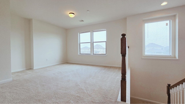 unfurnished room with a healthy amount of sunlight, baseboards, and light colored carpet